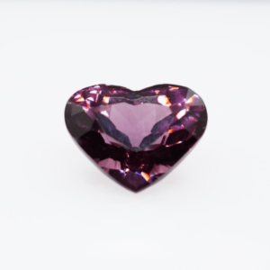 A heart-shaped purple gemstone with a brilliant faceted cut, displayed against a white background.